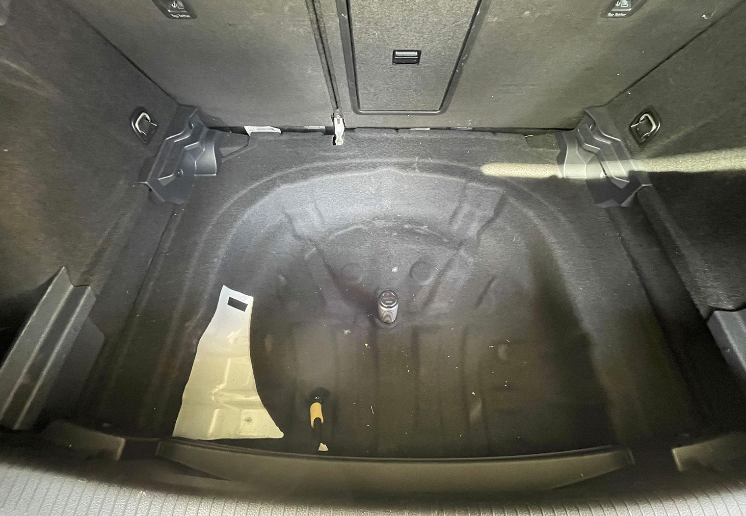 Picture of the OEM trunk space of a Volkswagen GTI MK7.5 with the spare tire and OEM fender subwoofer removed