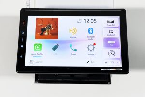 Pioneer SPHERA DMH-WT8000NEX powered on at the test bench, home screen up, with a coaxial speaker on each side