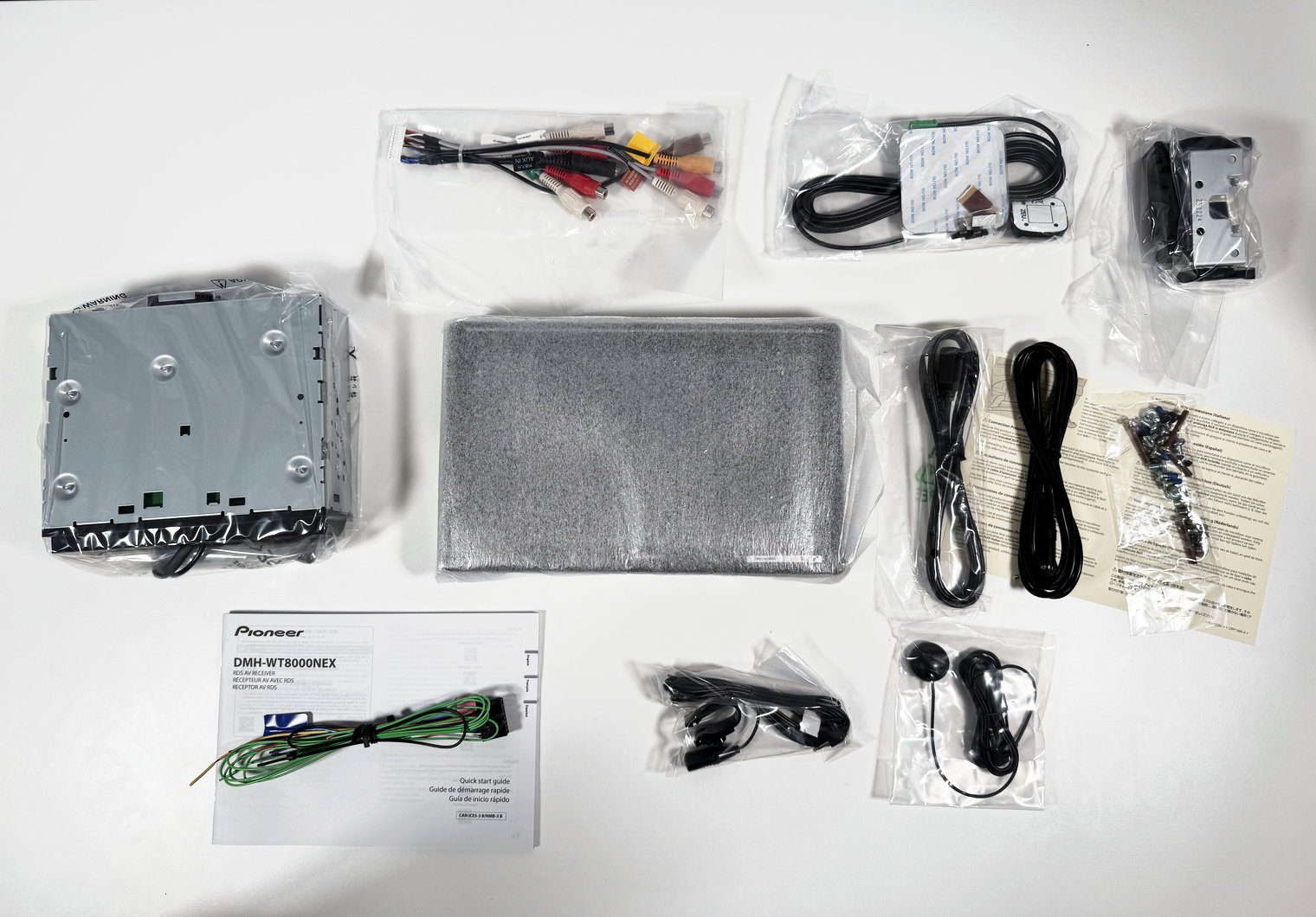 Everything in the Pioneer DMH-WT8000NEX box laid out, still bagged: chassis, monitor, harnesses, mics, GPS antenna and manual