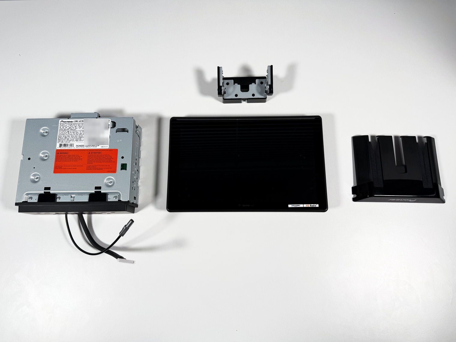 Pioneer DMH-WT8000NEX chassis, 10.1-inch monitor and mounting bracket parts unwrapped on a white table