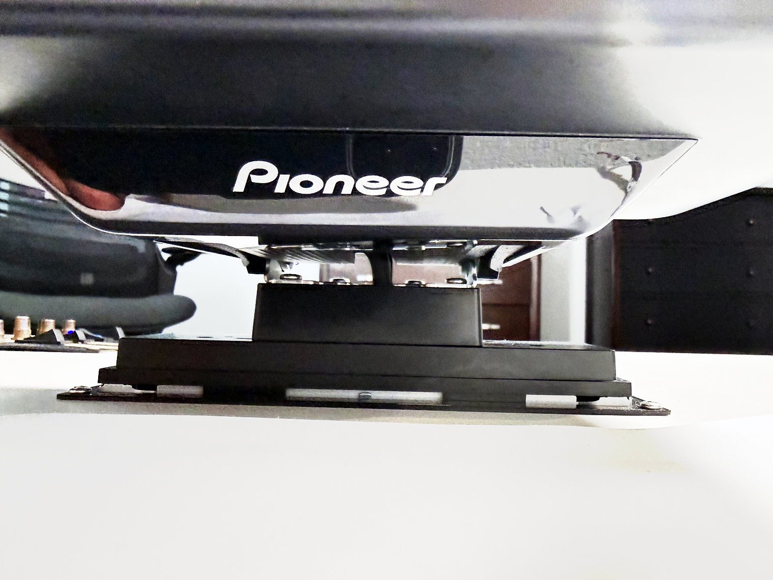 Low-angle view under the Pioneer DMH-WT8000NEX screen showing the hinge bracket that joins it to the chassis